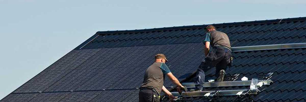 Two men installing solar panels on a roof