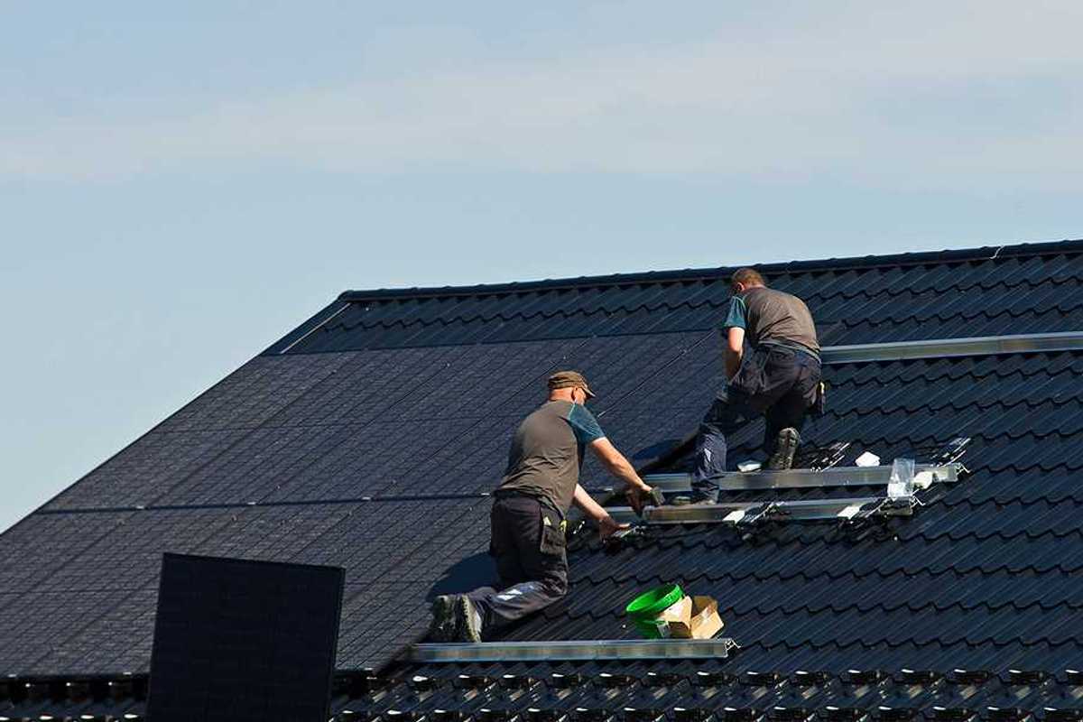 Two men installing solar panels on a roof