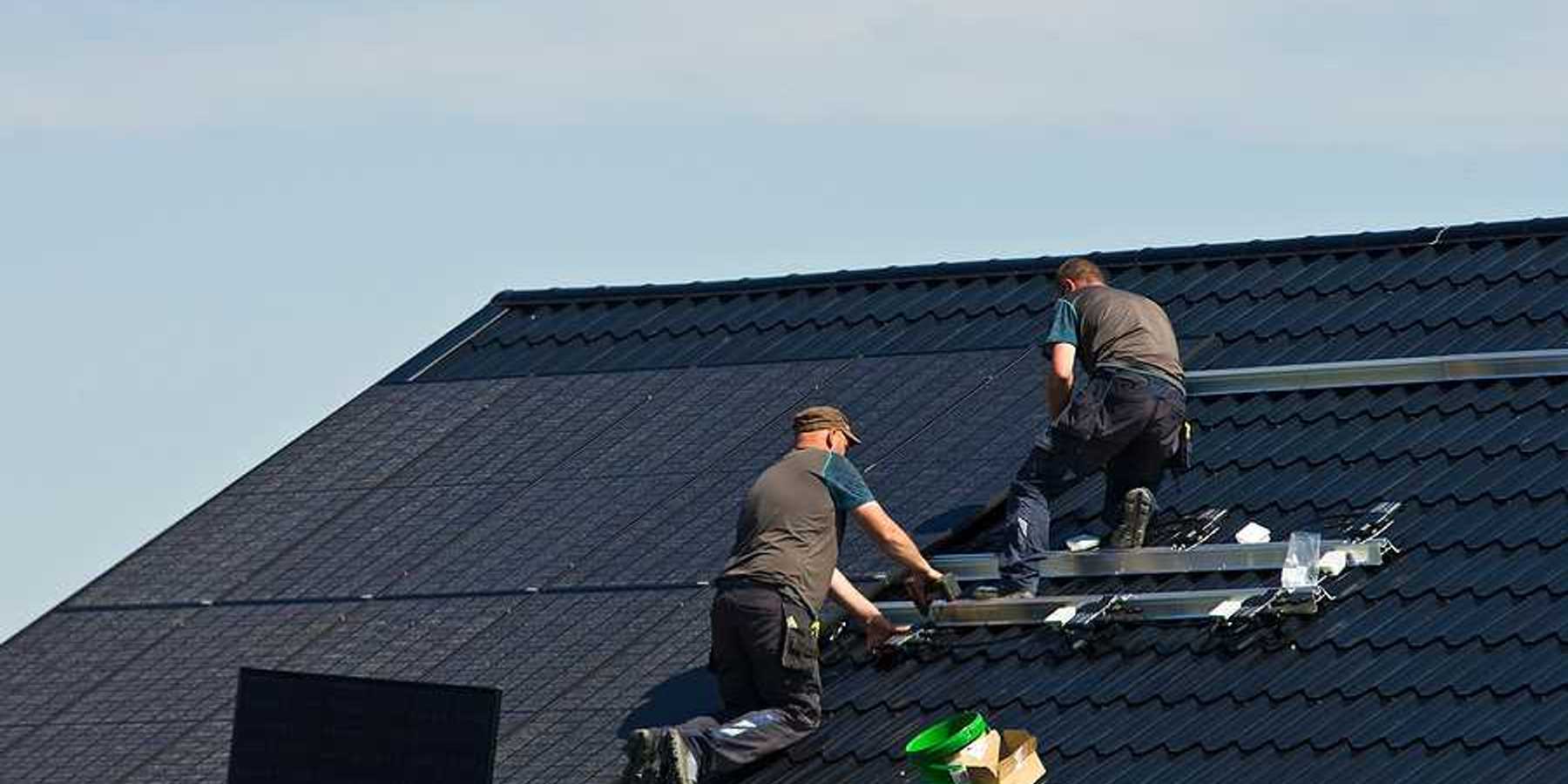 Two men installing solar panels on a roof
