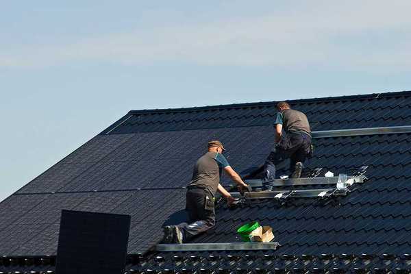 Two men installing solar panels on a roof