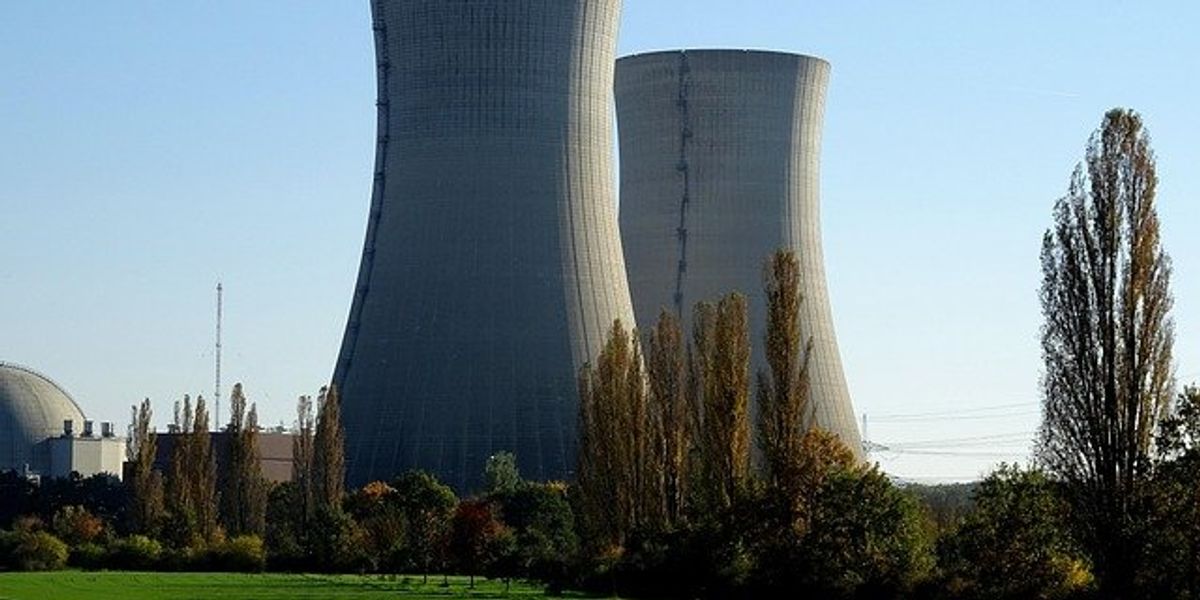 Two nuclear power reactors with a green field in the foreground.