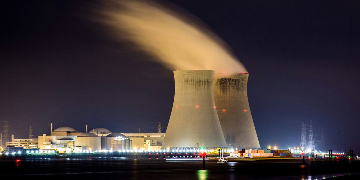 Two nuclear reactors at night with smoke emitting from the towers.