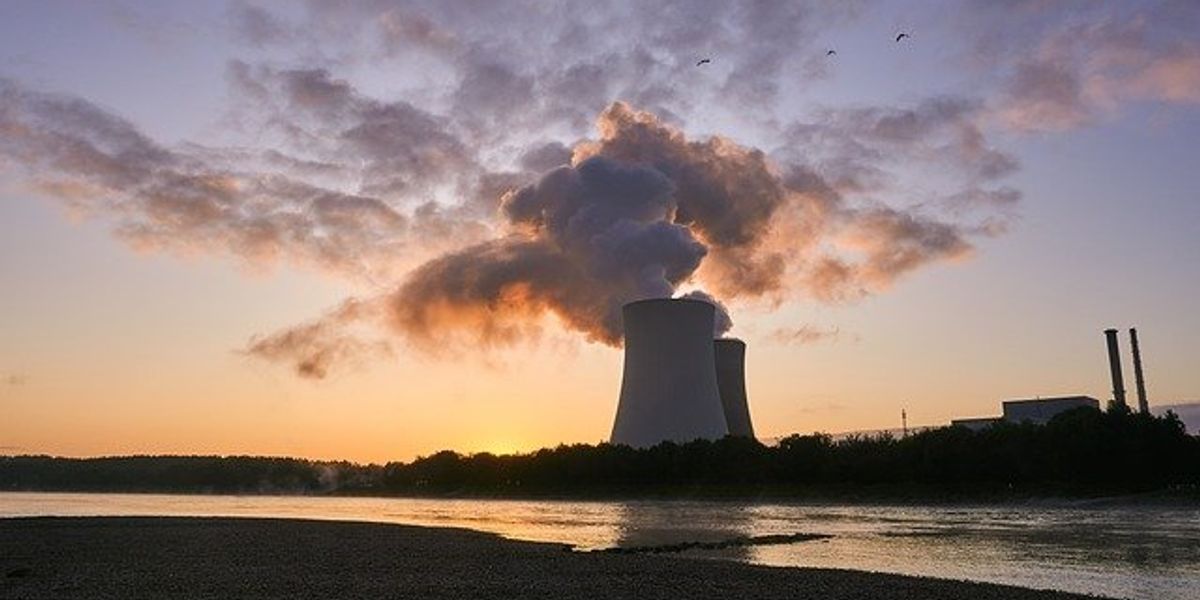 Two nuclear towers silhouetted under a cloudy sky at sunset.