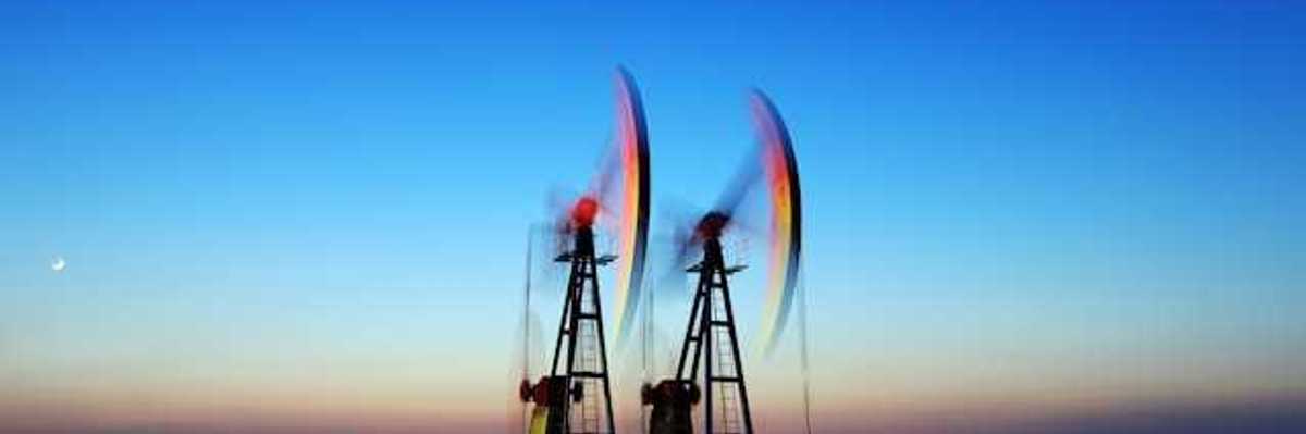 Two oil pump jacks against the setting sun