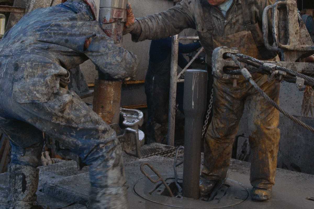 Two oilfield workers working on drilling equipment