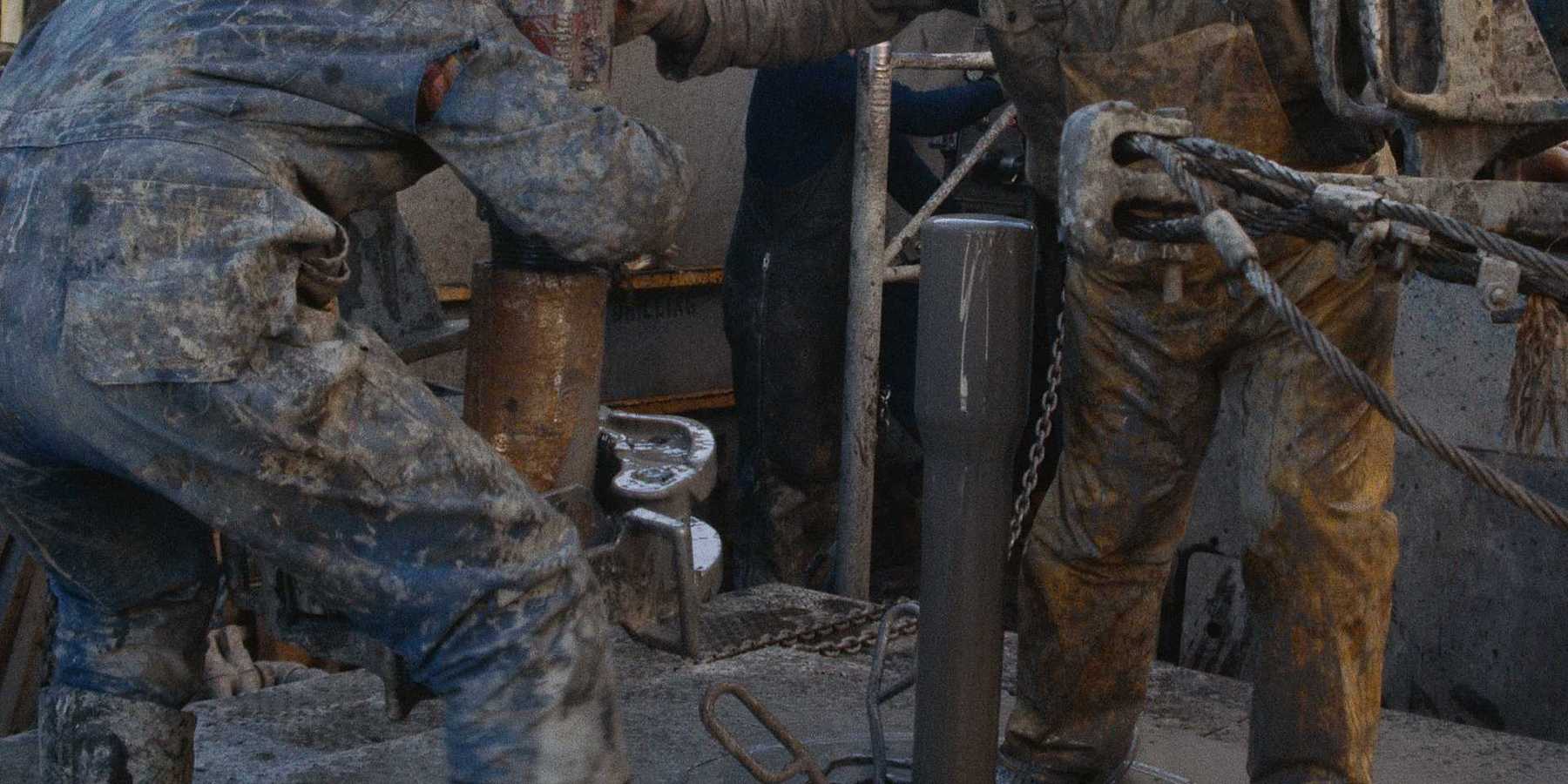 Two oilfield workers working on drilling equipment