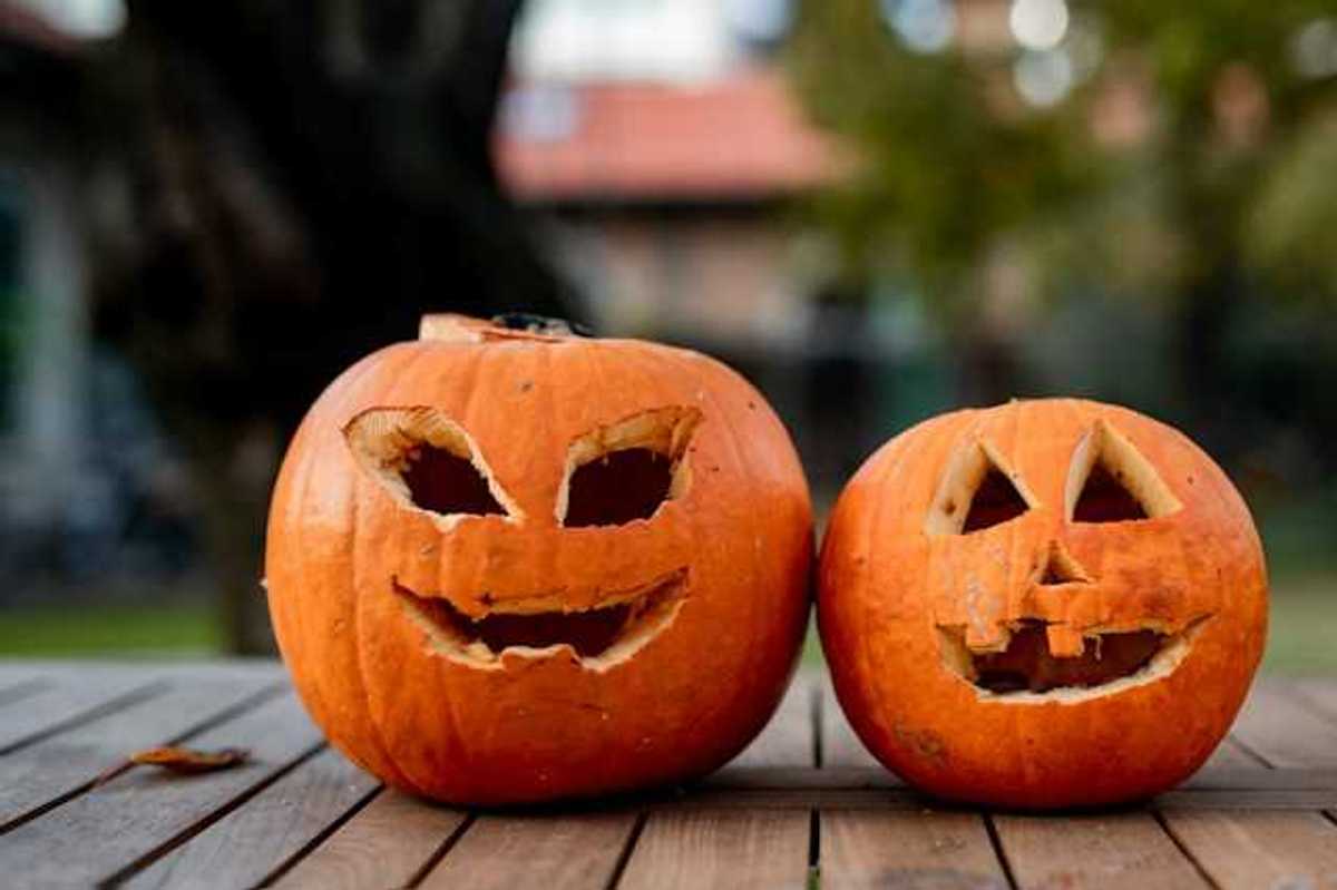 Two orange pumpkins with faces carved into them