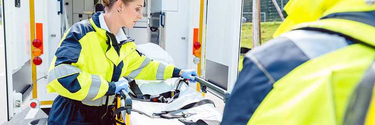 Two paramedics preparing a gurney outside of their ambulance