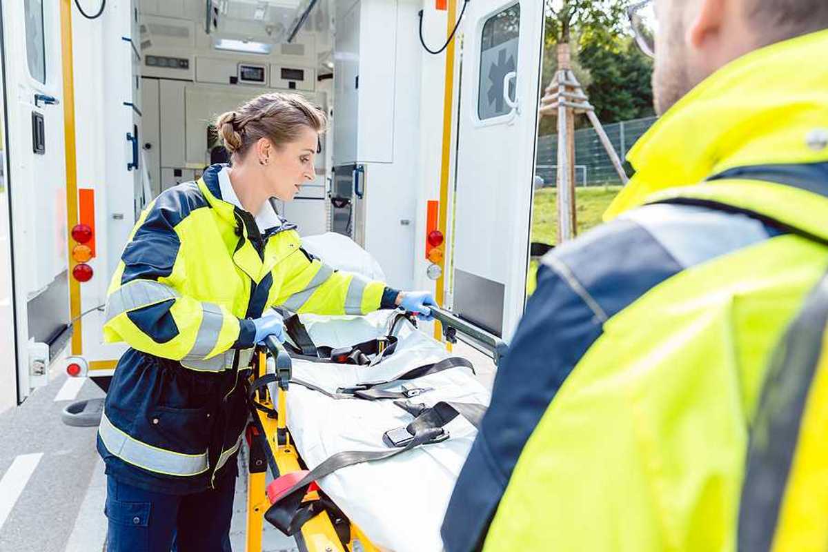 Two paramedics preparing a gurney outside of their ambulance