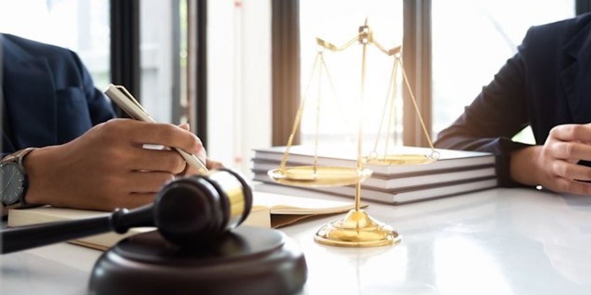 Two people at a desk with a judge's gavel and a model of the scales of justice
