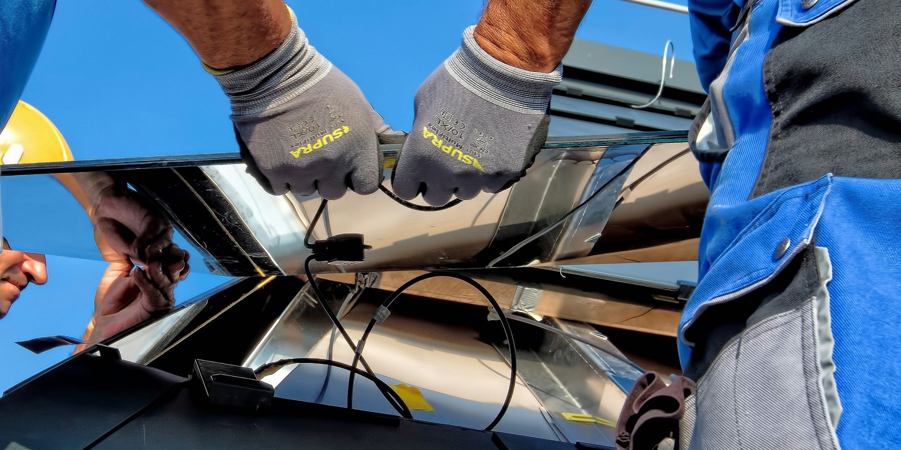 Two people installing a solar panel on a roof.