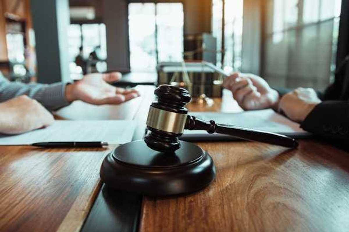 Two people sitting across from each other at a wooden table with a wooden gavel