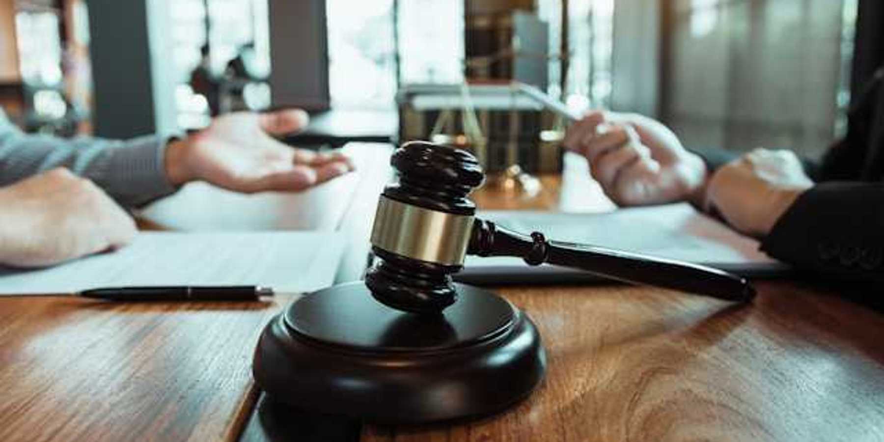 Two people sitting across from each other at a wooden table with a wooden gavel
