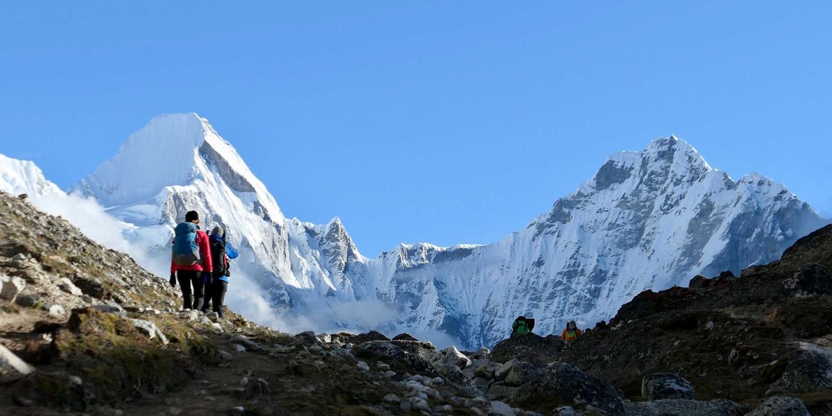 two person on mountain with snowy mountains in the background