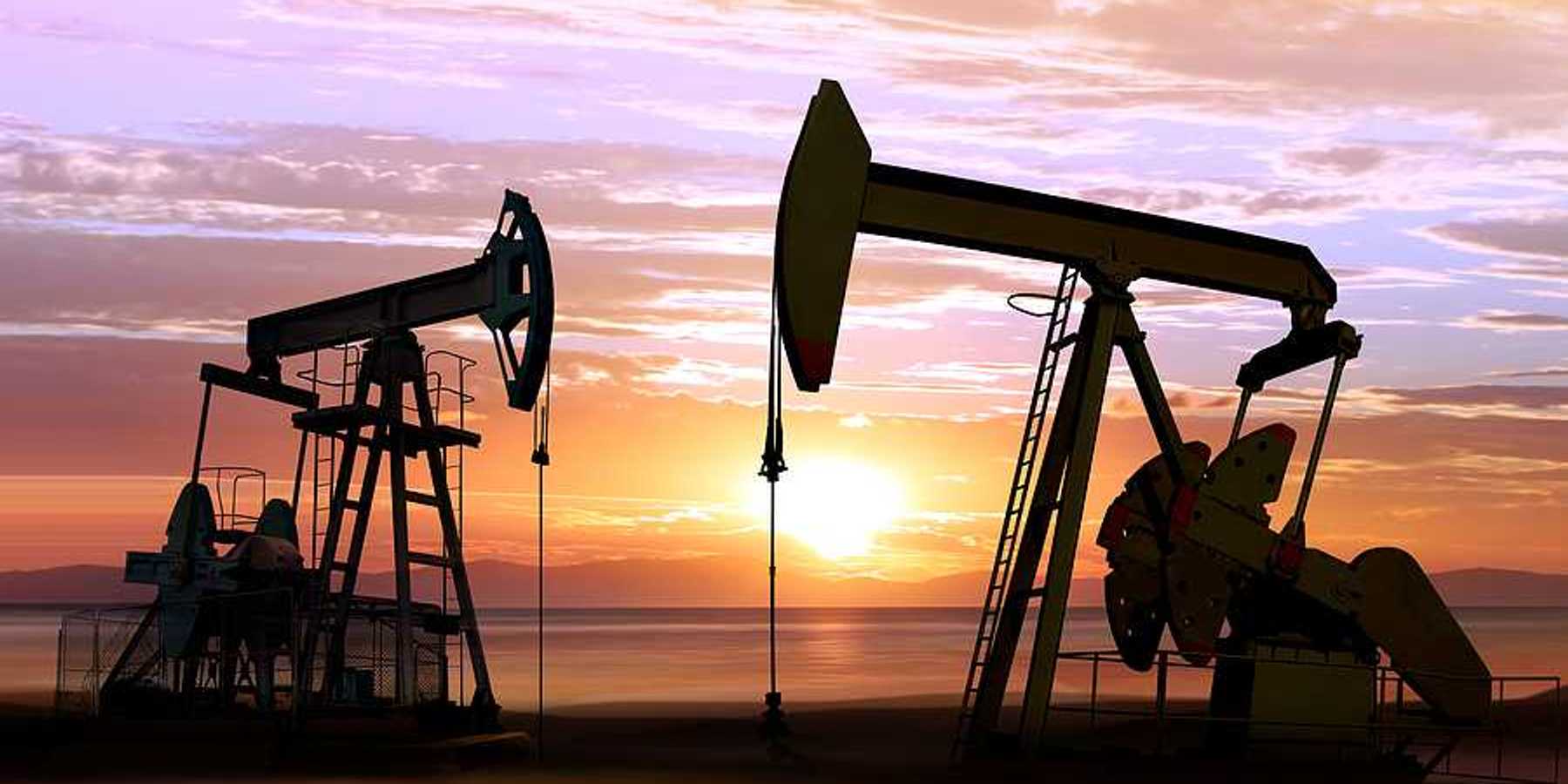 Two pump jacks against a sunset