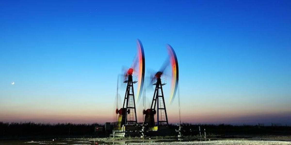 Two pump jacks pictured at dusk.