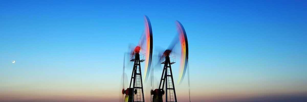 Two pumpjacks depicting blurred motion, surrounded by pools of standing water