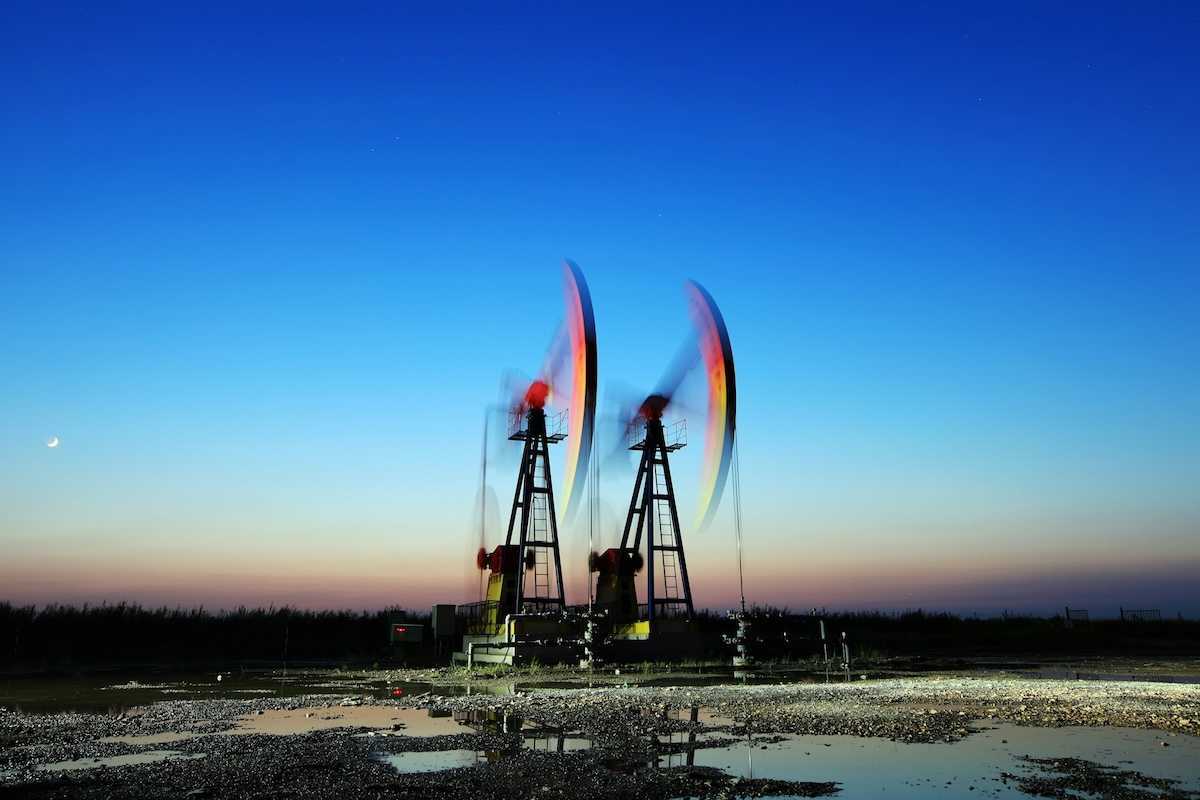 Two pumpjacks depicting blurred motion, surrounded by pools of standing water