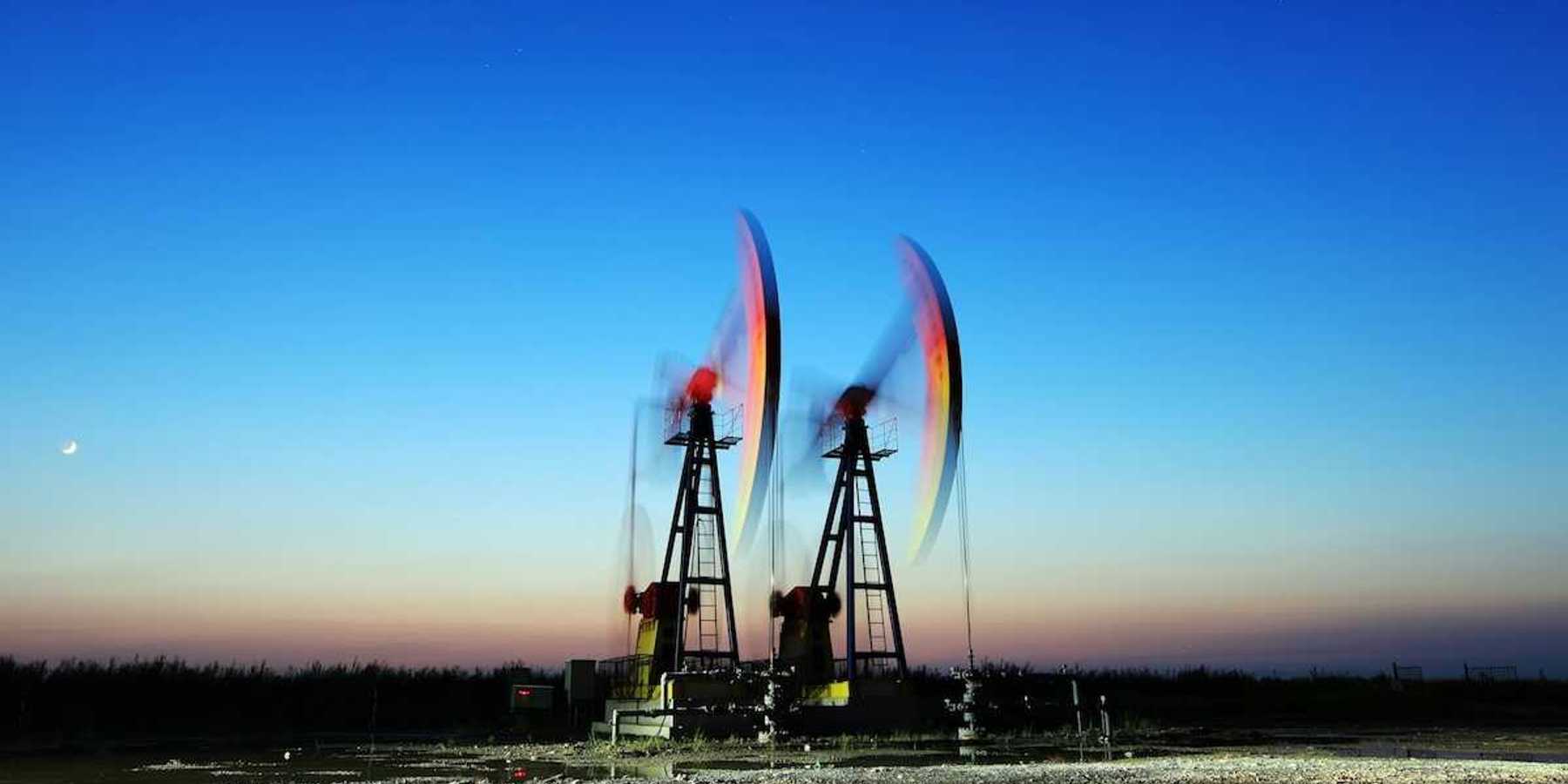 Two pumpjacks depicting blurred motion, surrounded by pools of standing water