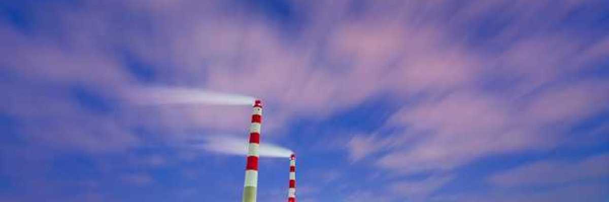 Two red and white mokestacks against a blue sky