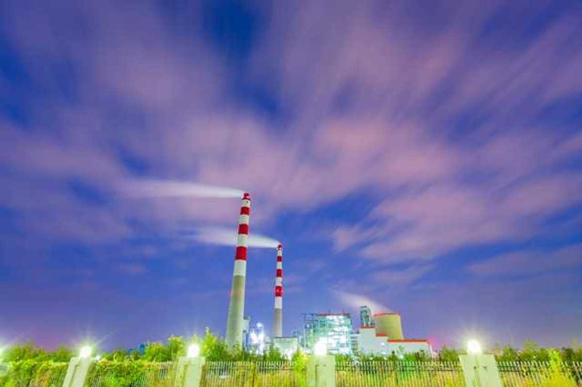 Two red and white mokestacks against a blue sky