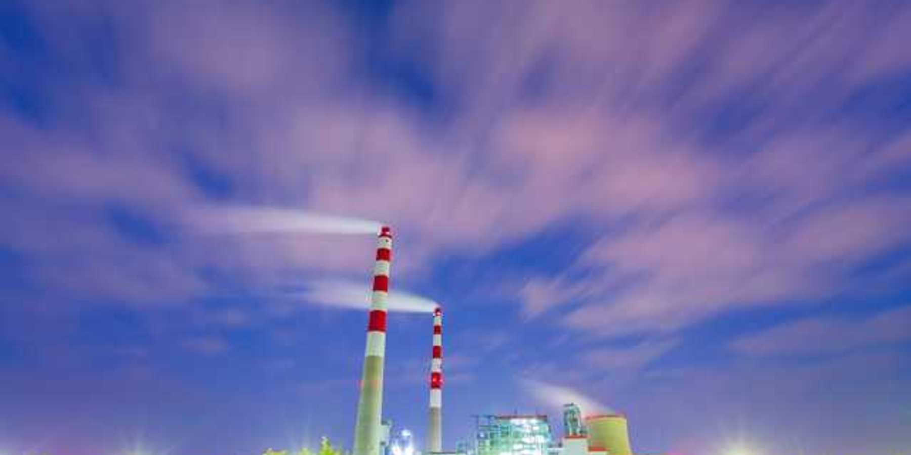 Two red and white mokestacks against a blue sky