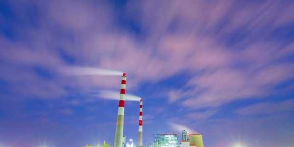 Two red and white mokestacks against a blue sky