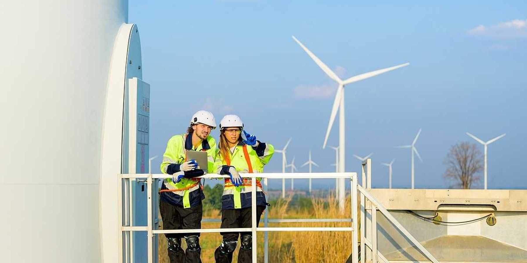Two renewable energy engineers working on a wind turbine.