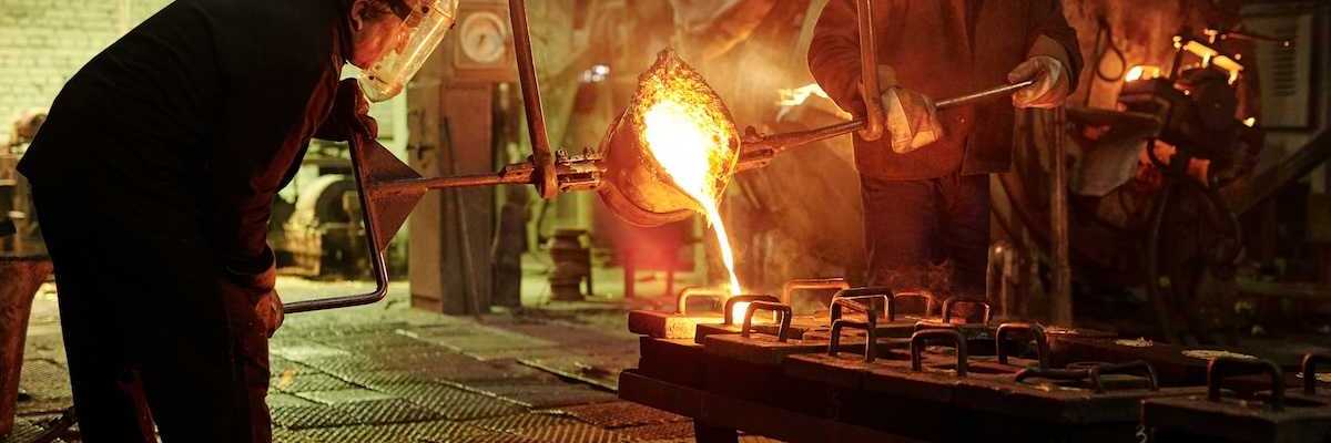 Two steel/iron foundry workers pouring molten material