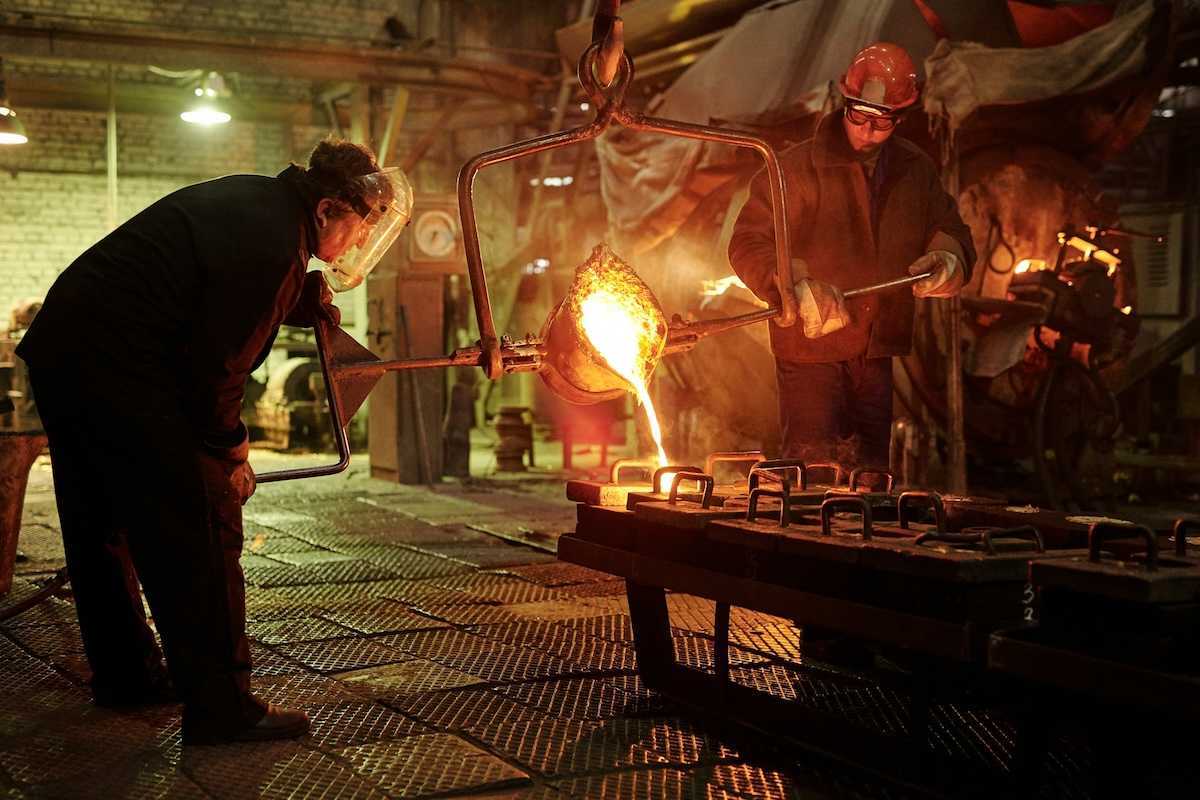 Two steel/iron foundry workers pouring molten material