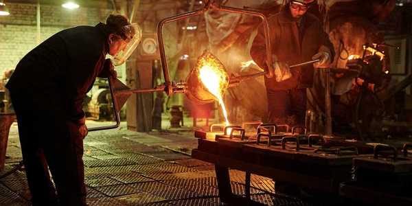 Two steel/iron foundry workers pouring molten material