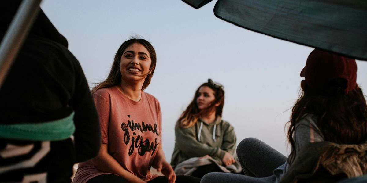 Two women sitting outside with a group