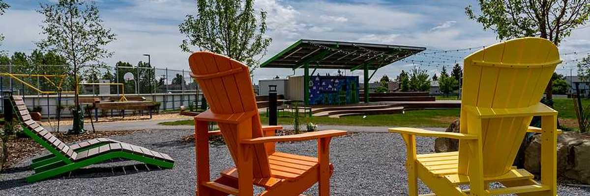 Two wooden chairs next to a field that has a solar shade panel over it