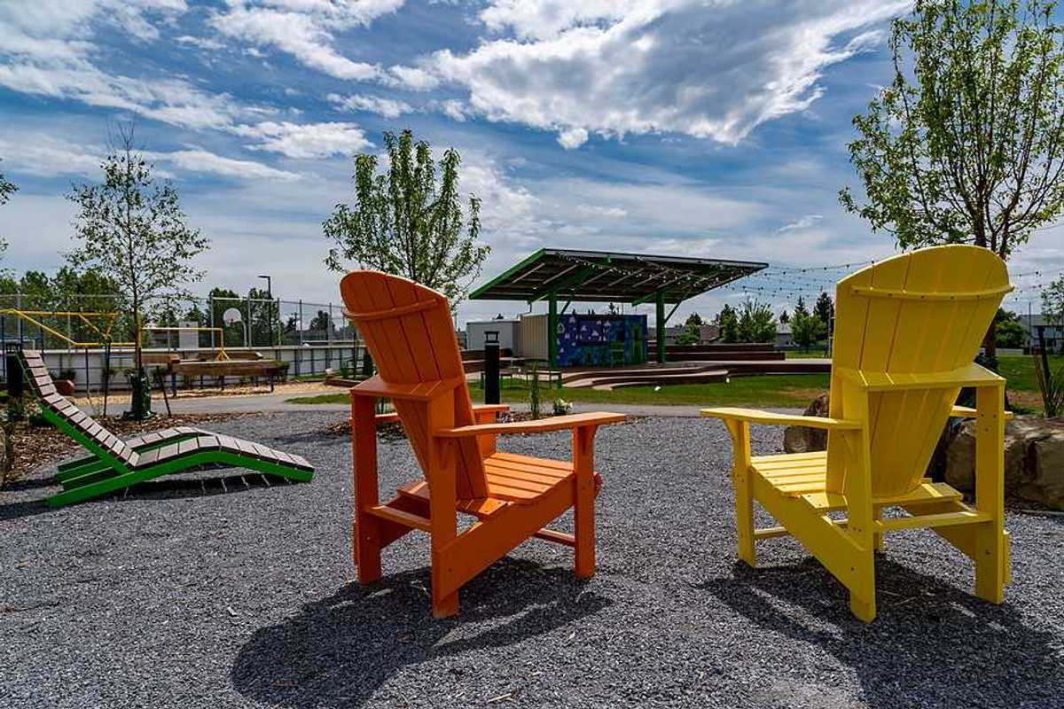 Two wooden chairs next to a field that has a solar shade panel over it