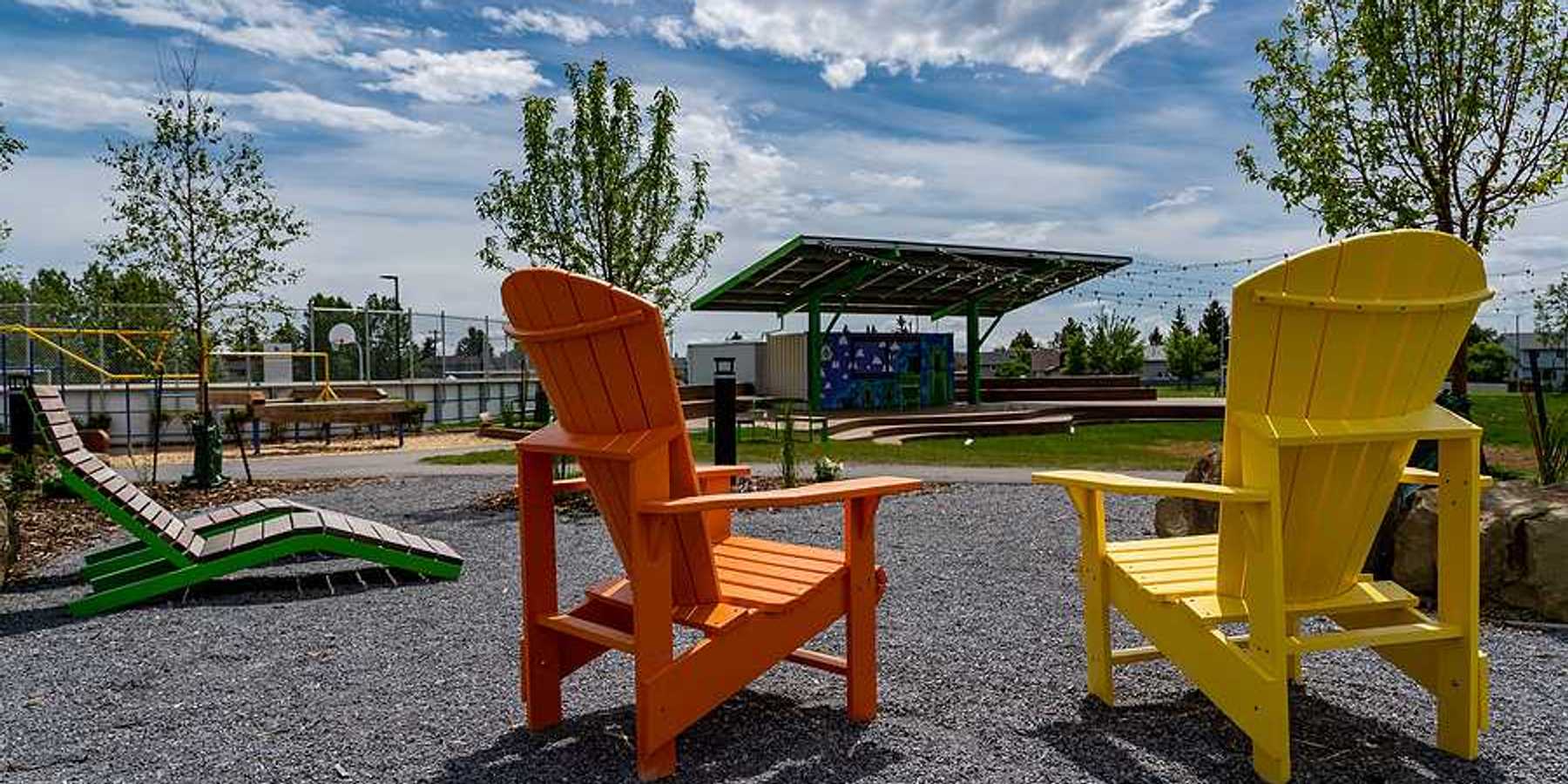 Two wooden chairs next to a field that has a solar shade panel over it