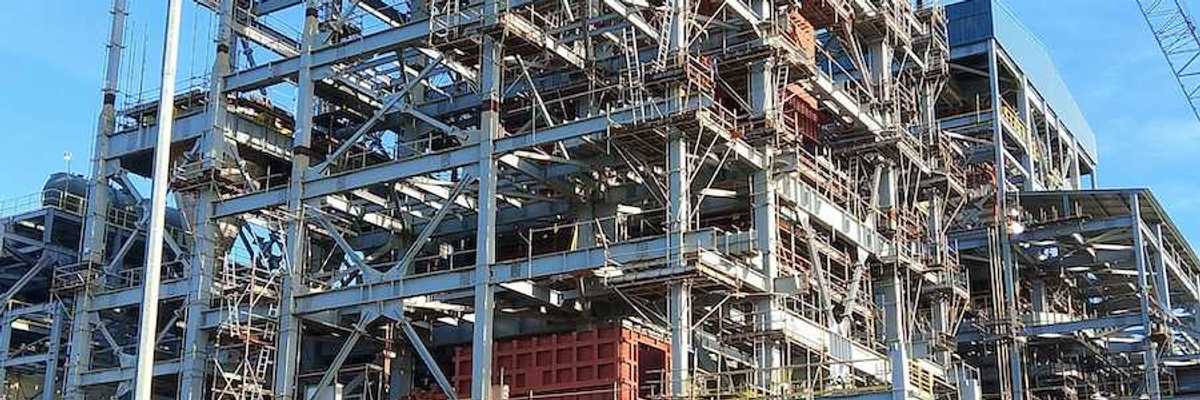 Two workers walk towards an industrial site under construction