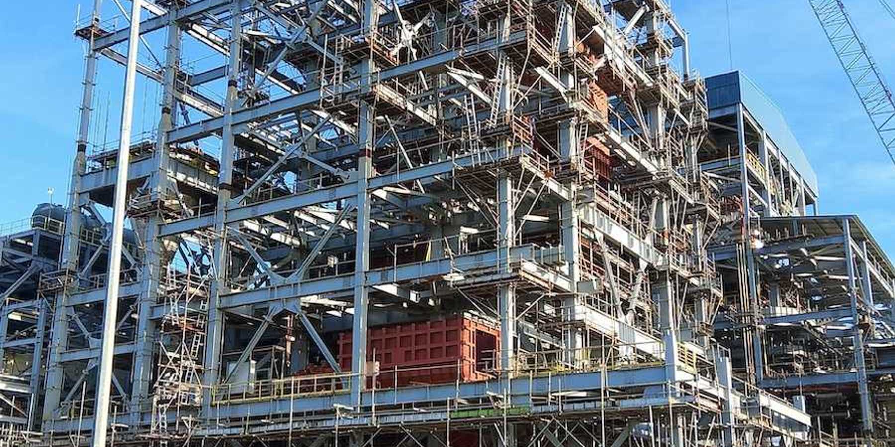 Two workers walk towards an industrial site under construction