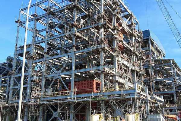 Two workers walk towards an industrial site under construction