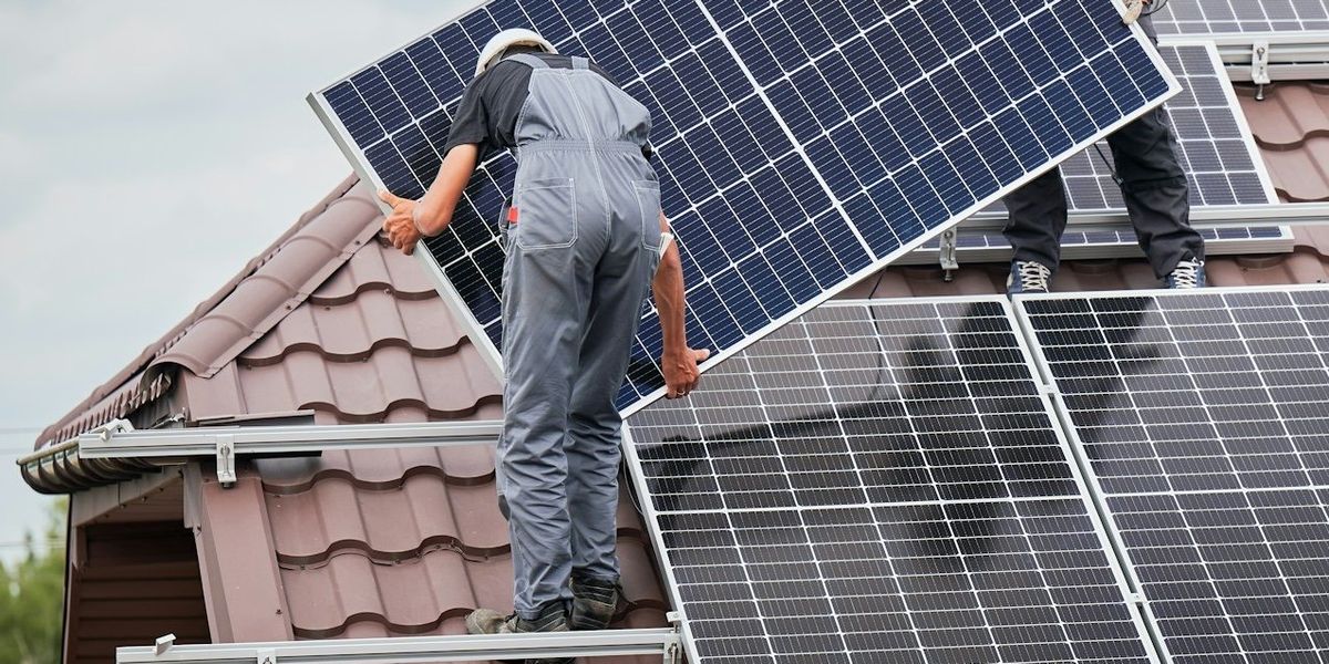 Two workmen installing rooftop solar panels