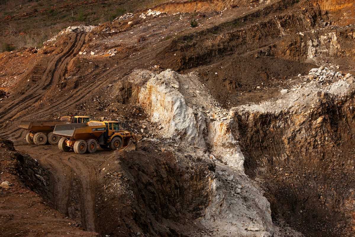 Two yellow rock trucks parked in a lithium mining cut
