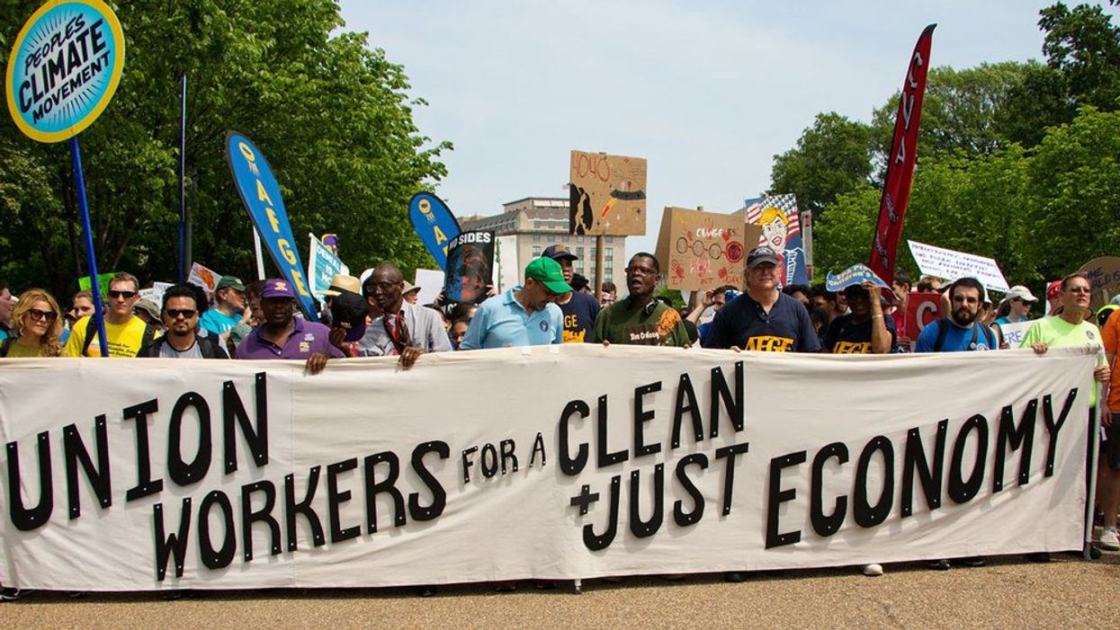 Union Workers walking with a large banner that says "Union Workers for a Clean + Just Economy" at a rally in Washington DC