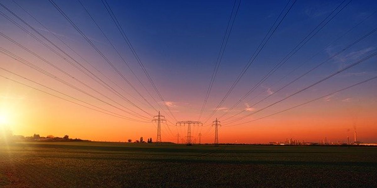 Utility towers and power lines stretching into the distance at sunset.