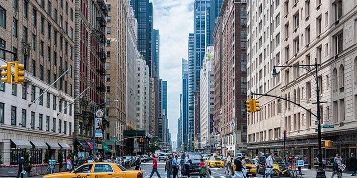 View of a Manhattan street with cars, pedestrians, and skyscrapers.