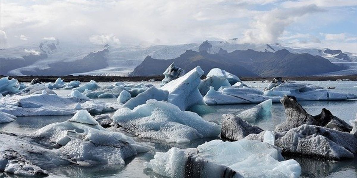 View of small icebergs floating on the water with dark mountains in the background.