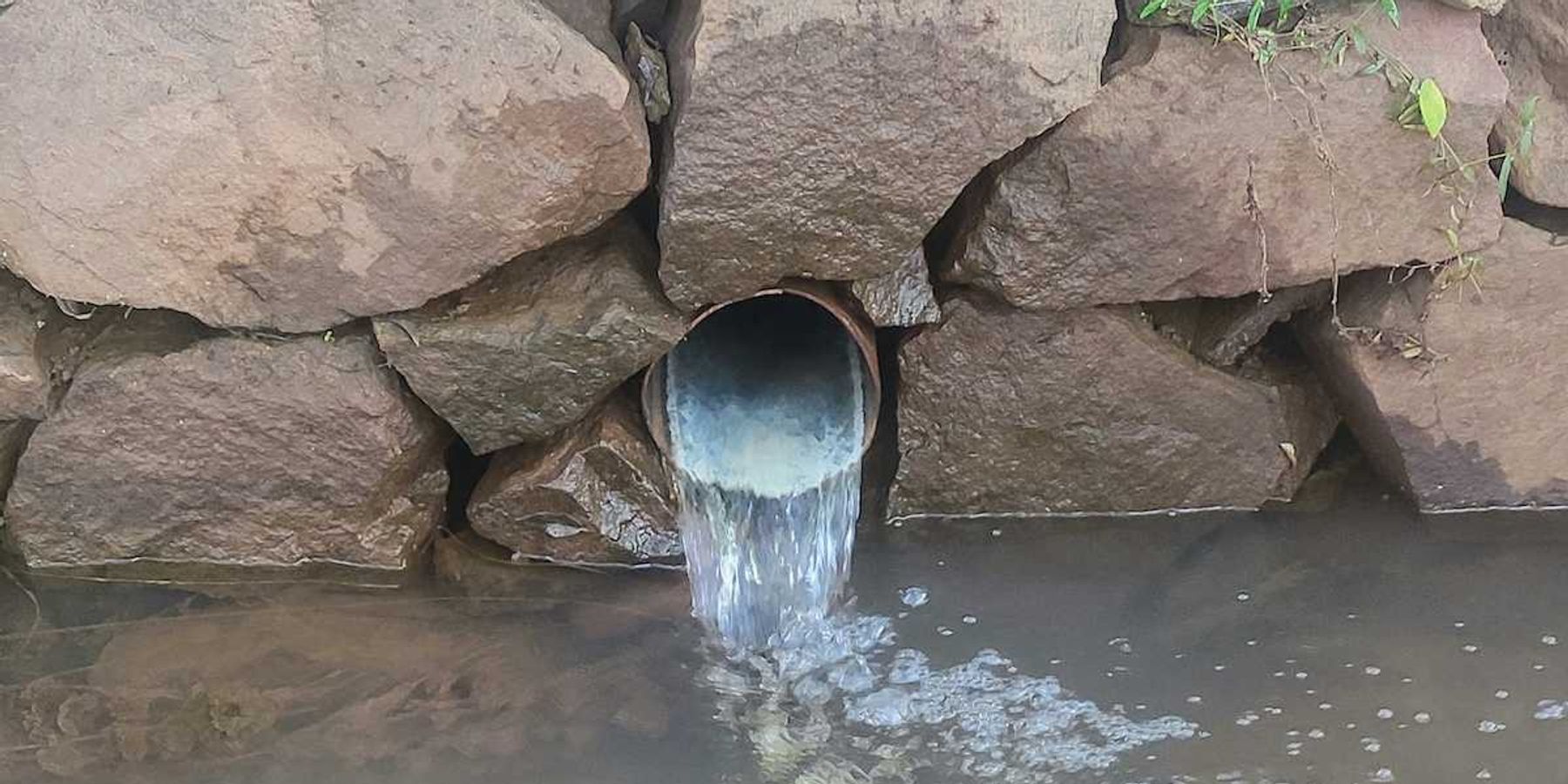 Wastewater flowing from outflow into pond