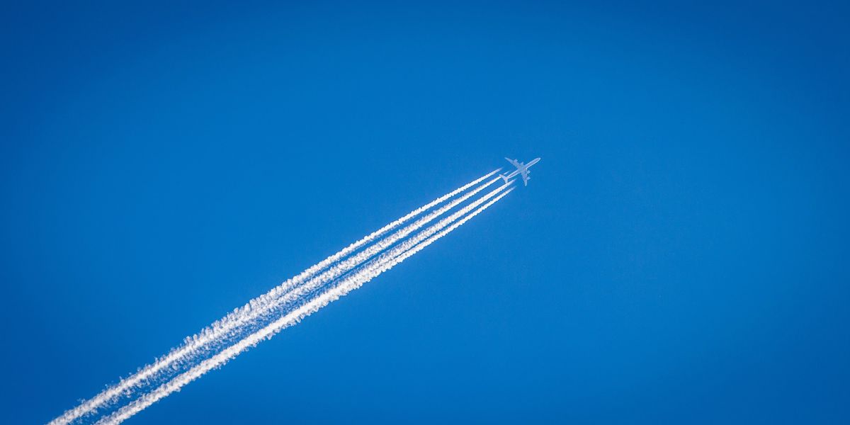 white airplane flying under the blue sky