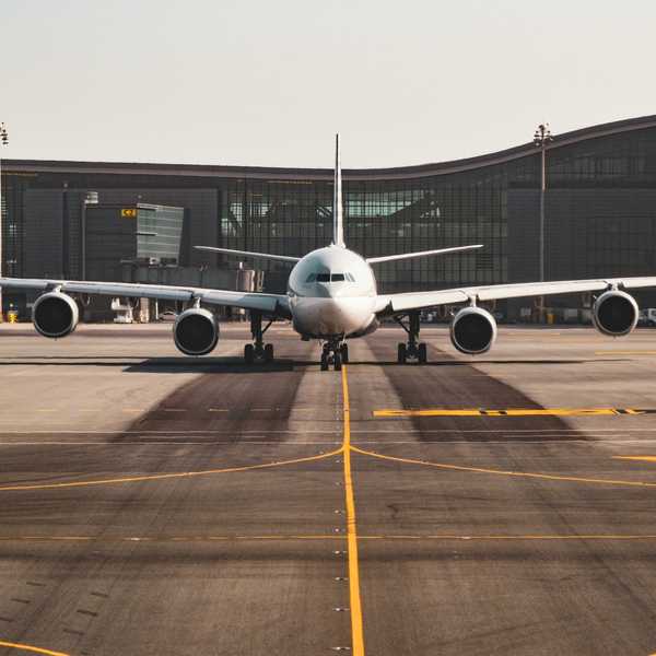 White airplane viewed from the front on the tarmac with an airport terminal in the background