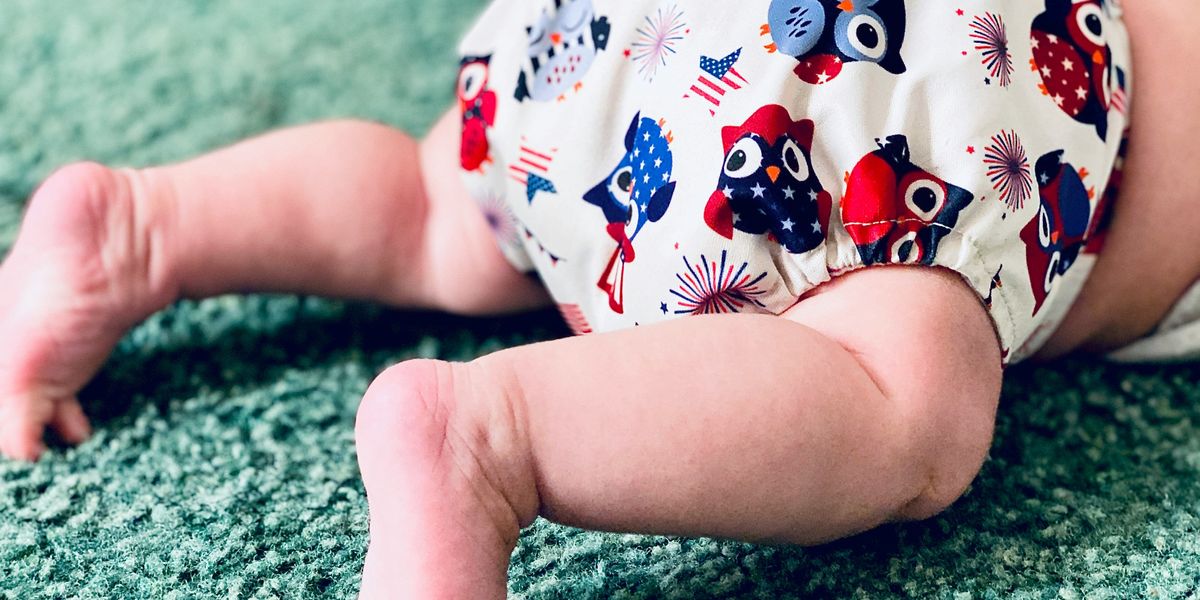 white and red owl print diaper on a crawling baby