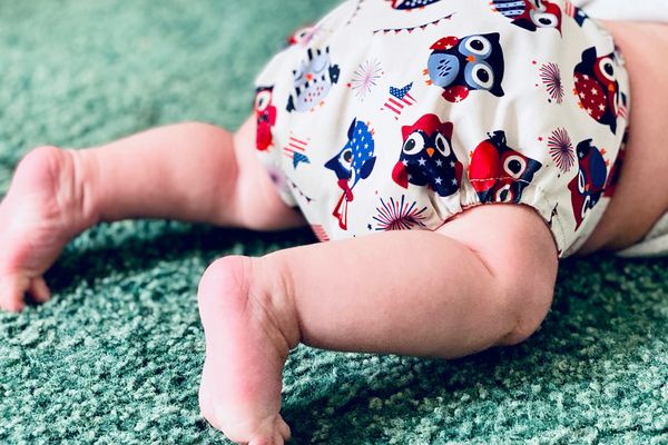 white and red owl print diaper on a crawling baby
