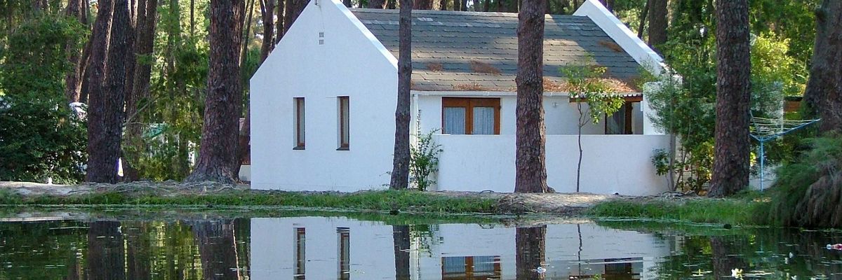 white house on forest with floodwaters in foreground.